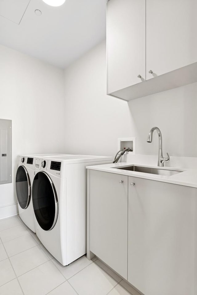 laundry area with cabinet space, electric panel, washing machine and clothes dryer, a sink, and light tile patterned flooring