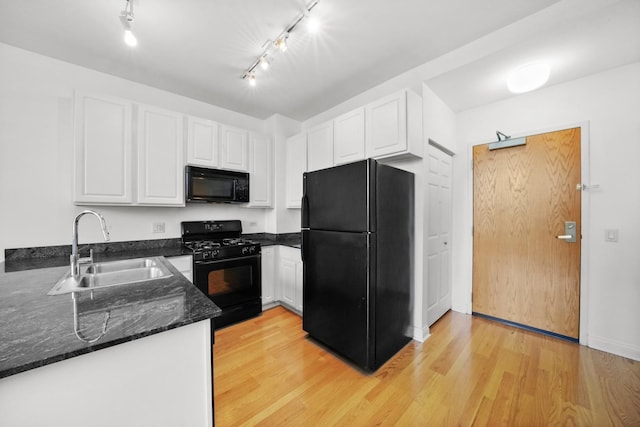 kitchen with white cabinetry, dark stone countertops, black appliances, light hardwood / wood-style flooring, and sink