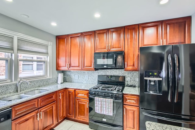 kitchen featuring light tile patterned floors, backsplash, black appliances, light stone counters, and sink