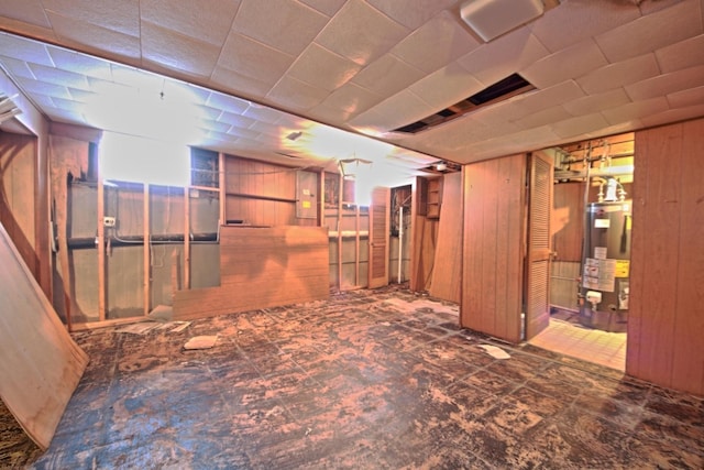 basement featuring gas water heater and wood walls