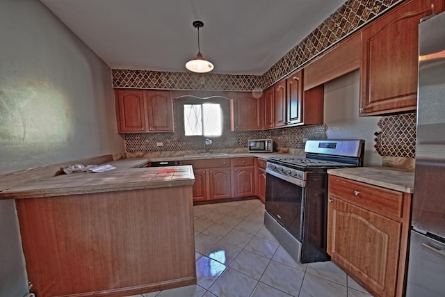 kitchen with pendant lighting, appliances with stainless steel finishes, sink, and light tile patterned floors