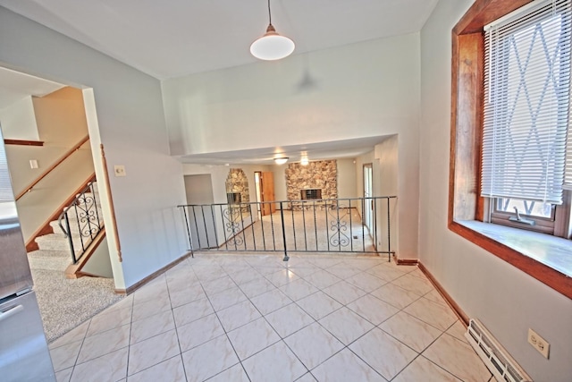 interior space with a baseboard heating unit, light tile patterned floors, and a fireplace