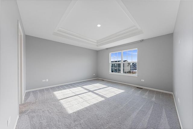 empty room with a raised ceiling and carpet