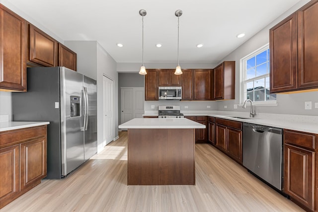 kitchen with sink, a center island, light wood-type flooring, appliances with stainless steel finishes, and pendant lighting