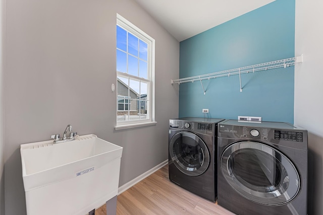 washroom with washing machine and clothes dryer, sink, and light hardwood / wood-style flooring