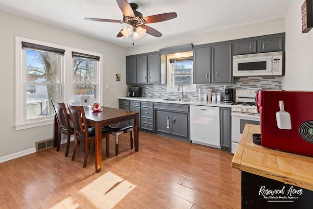 kitchen featuring sink, white appliances, gray cabinets, and light wood-type flooring