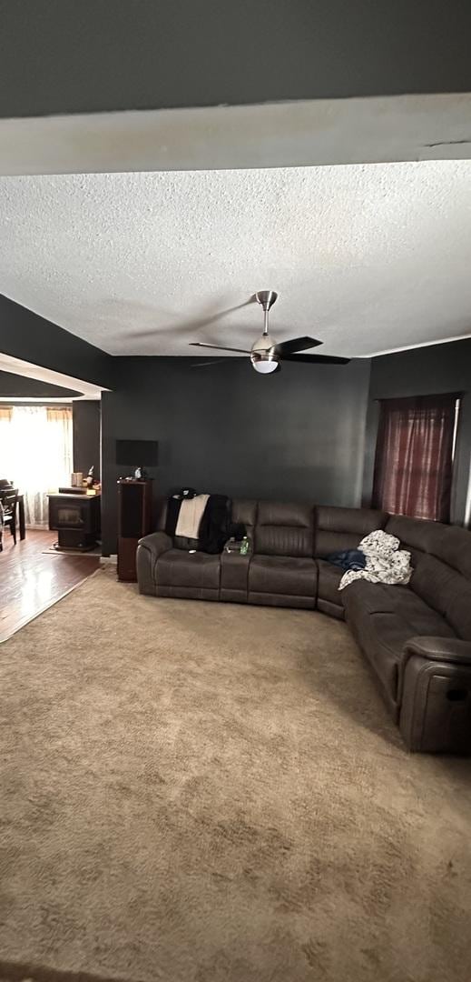 carpeted living room featuring ceiling fan and a textured ceiling