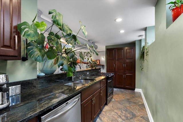 kitchen featuring sink, appliances with stainless steel finishes, dark brown cabinets, and dark stone countertops