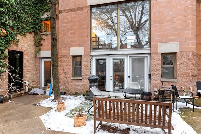 snow covered back of property featuring a patio area