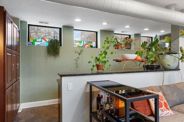 kitchen with kitchen peninsula and dark stone countertops