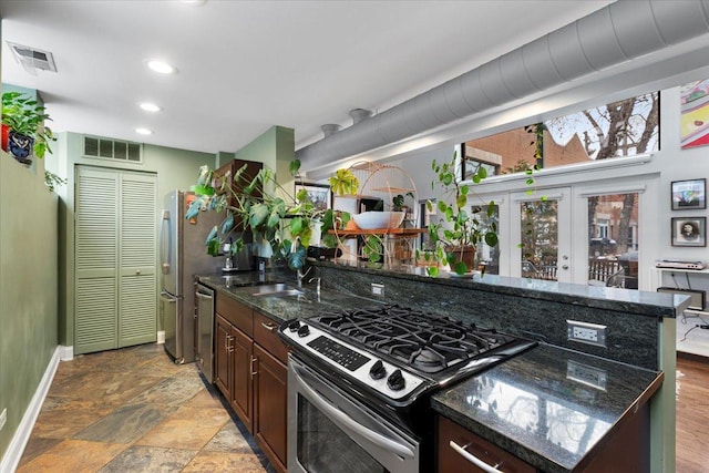 kitchen featuring sink, stainless steel appliances, dark brown cabinetry, and dark stone counters