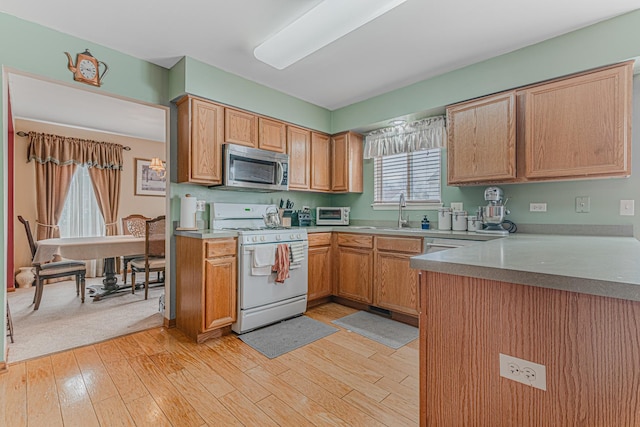 kitchen featuring light wood-type flooring, white gas stove, and sink