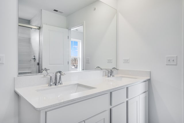 full bathroom featuring a shower with shower door, visible vents, a sink, and double vanity