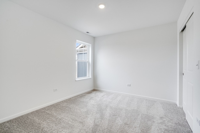 empty room featuring light carpet, recessed lighting, visible vents, and baseboards