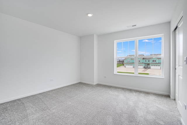 spare room with carpet, visible vents, and baseboards