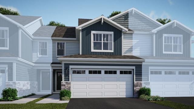 view of front of home with board and batten siding, stone siding, driveway, and a garage