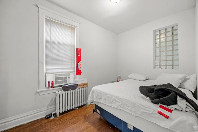 bedroom featuring cooling unit, hardwood / wood-style flooring, and radiator heating unit