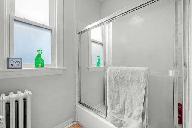 bathroom featuring bath / shower combo with glass door and radiator heating unit