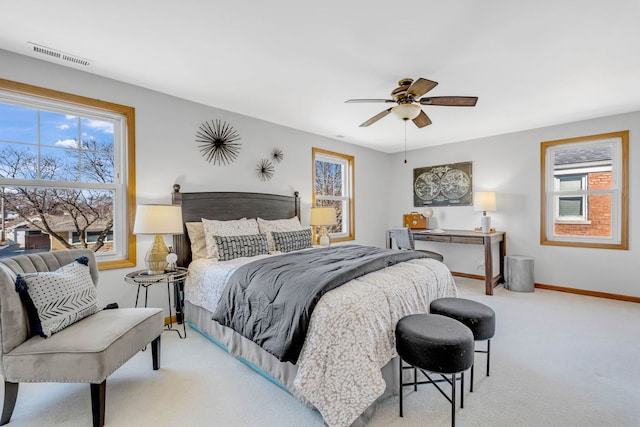 bedroom featuring baseboards, multiple windows, visible vents, and light colored carpet