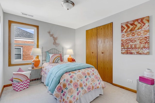 bedroom with baseboards, visible vents, a closet, and light colored carpet