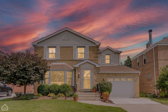 traditional-style home featuring roof with shingles, a yard, brick siding, concrete driveway, and a garage