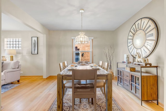 dining area featuring light wood-style floors, a chandelier, and baseboards