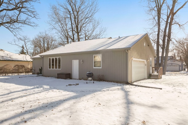 snow covered back of property with a garage