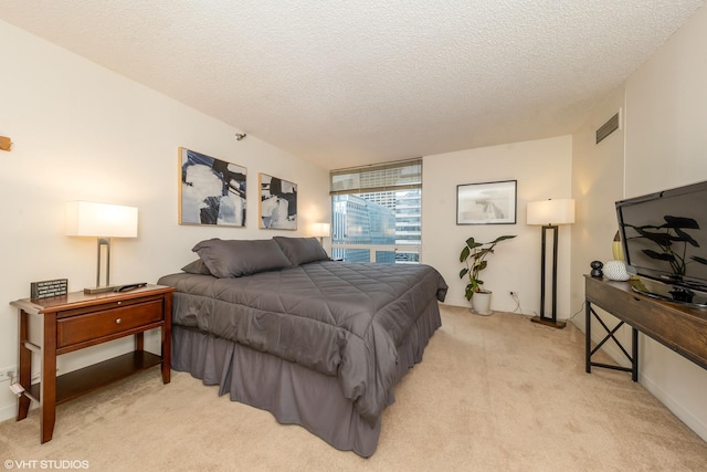 bedroom with a textured ceiling and light colored carpet