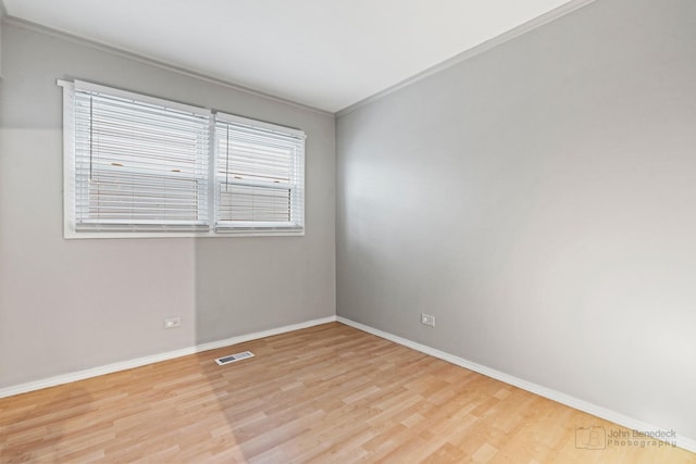 empty room with ornamental molding and light hardwood / wood-style floors