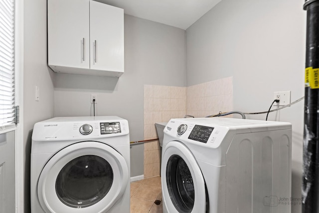 washroom featuring independent washer and dryer, cabinets, and light tile patterned floors