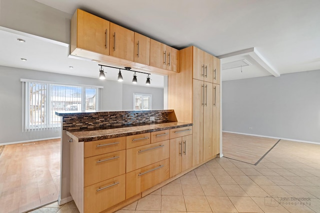 kitchen featuring light brown cabinetry, dark stone countertops, kitchen peninsula, backsplash, and light tile patterned flooring