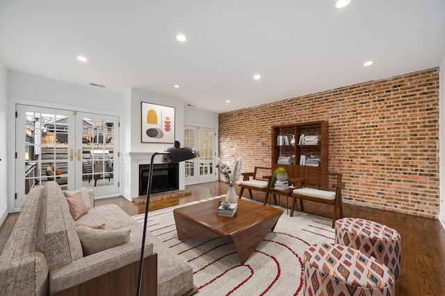 living room featuring french doors, brick wall, and hardwood / wood-style flooring