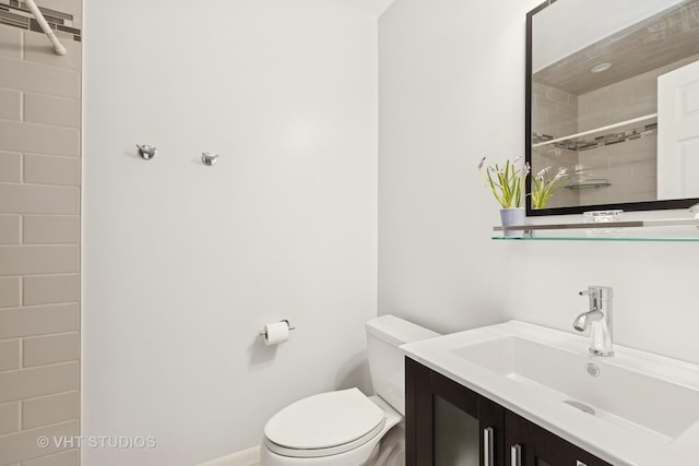 bathroom with vanity, tiled shower, and toilet