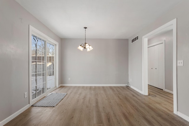 unfurnished dining area with an inviting chandelier and light wood-type flooring