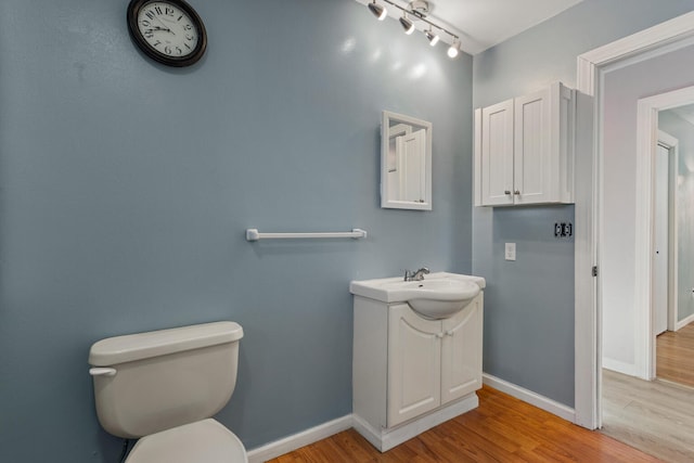 bathroom featuring vanity, hardwood / wood-style floors, track lighting, and toilet