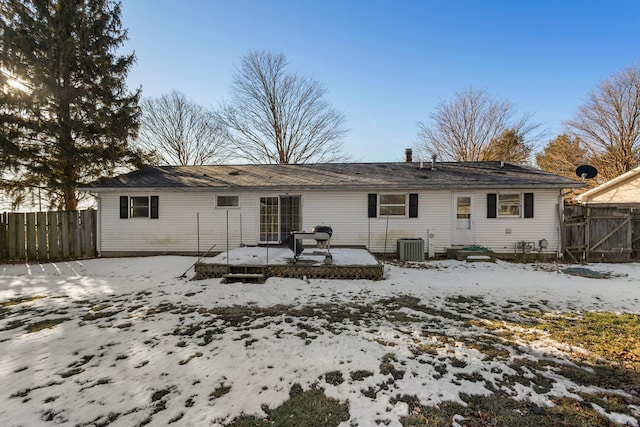 snow covered rear of property with a wooden deck and central AC