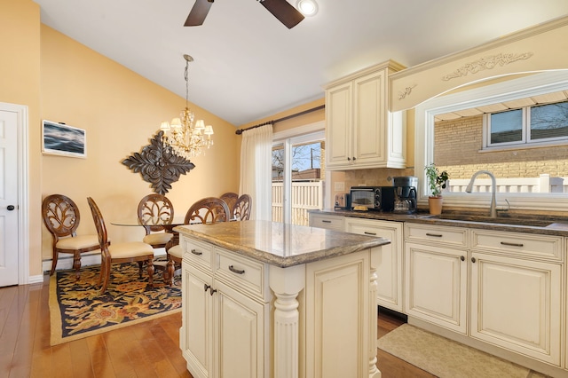 kitchen featuring pendant lighting, a center island, sink, cream cabinets, and light wood-type flooring