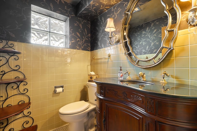 bathroom with toilet, vanity, tile patterned floors, and tile walls