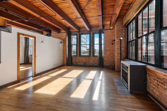 interior space featuring beam ceiling, wood-type flooring, wooden ceiling, and brick wall