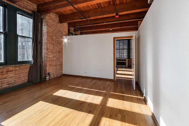 unfurnished room with wood-type flooring, brick wall, wood ceiling, and beam ceiling