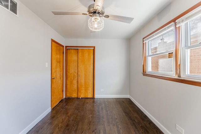 unfurnished bedroom featuring a closet, ceiling fan, dark hardwood / wood-style floors, and multiple windows