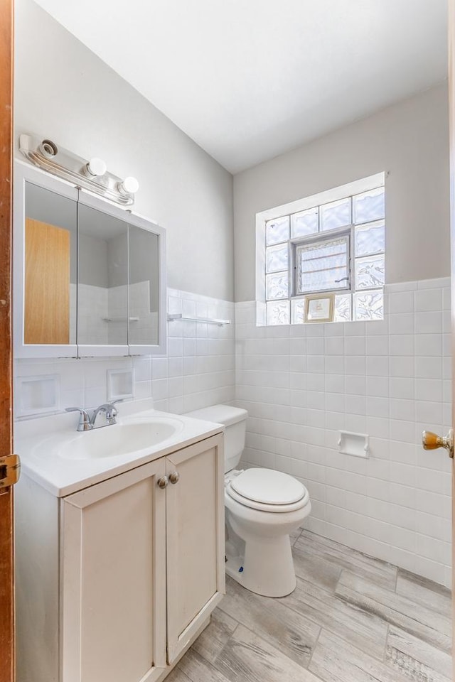 bathroom with vanity, toilet, tile walls, and hardwood / wood-style flooring