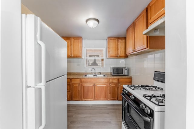 kitchen with light hardwood / wood-style floors, sink, white appliances, and tasteful backsplash