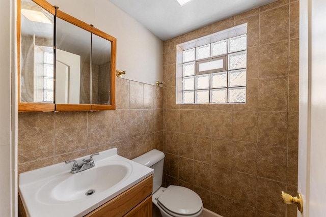 bathroom featuring tile walls, toilet, and vanity