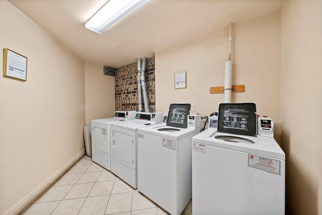 clothes washing area with washing machine and dryer and light tile patterned floors