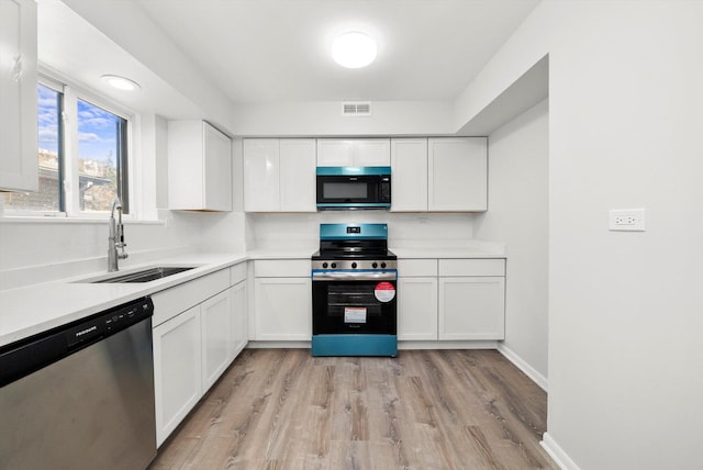 kitchen featuring sink, white cabinetry, light hardwood / wood-style flooring, and appliances with stainless steel finishes