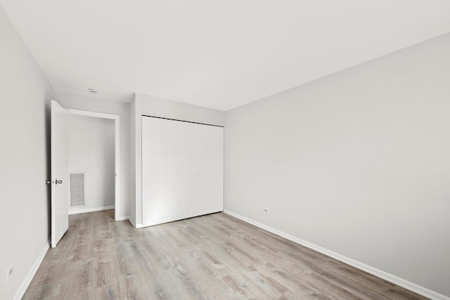 unfurnished bedroom featuring light wood-type flooring and a closet