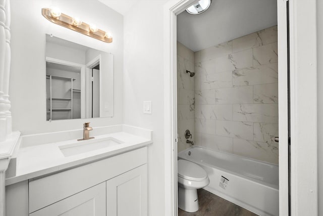 full bathroom featuring hardwood / wood-style floors, toilet, tiled shower / bath, and vanity