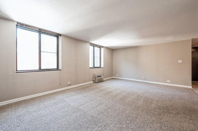 carpeted spare room with a wall unit AC and a textured ceiling