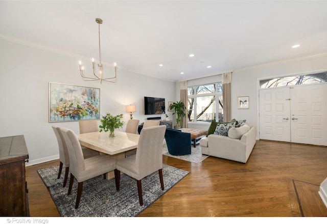 dining room with hardwood / wood-style floors, crown molding, and a notable chandelier